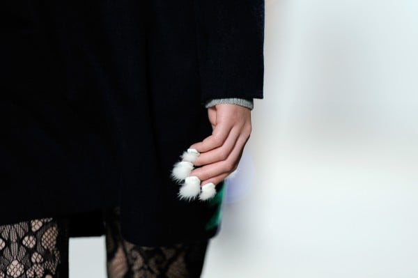 mujer caminando por una pasarela con uñas peludas en su mano 