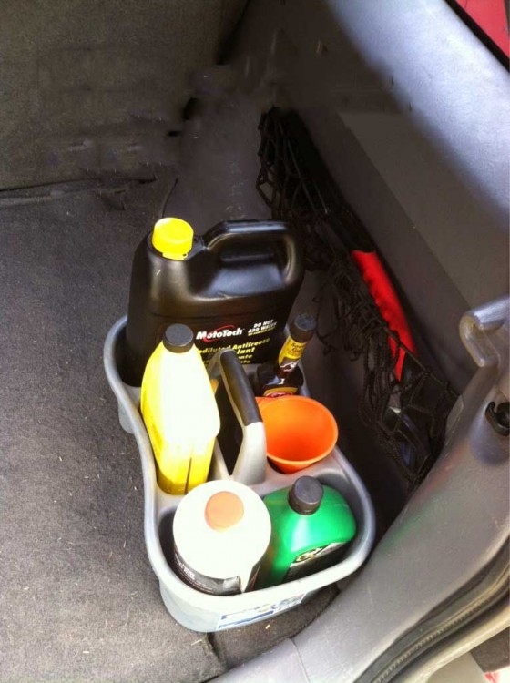 fluidos de un coche organizados dentro de una canasta de ducha 