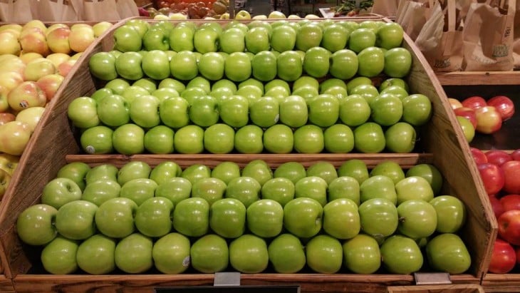manzanas verdes ordenadas sobre un estante en un centro comercial 