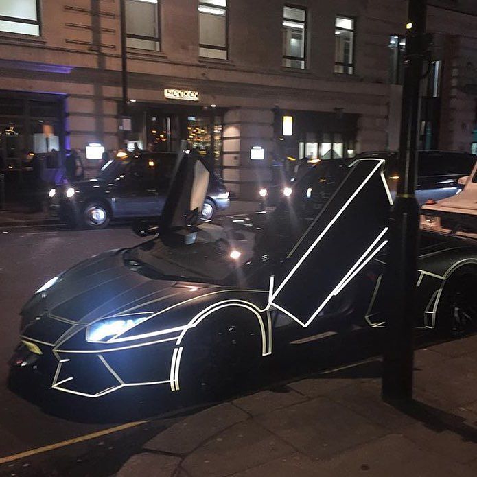 Carro lujoso rodeado de luces de neon en una de las calles de Londres 