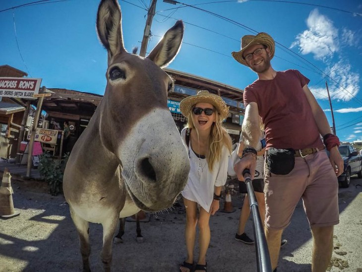 selfie de dos chicos que viajan alrededor del mundo en su furgoneta a lado de un burro 