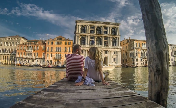 Pareja de Bloggers sentados en un muelle en Venecia, Italia 