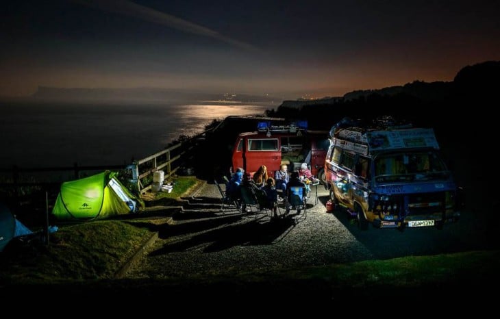 Personas en la noche cerca de montañas con casas de campañas y furgonetas