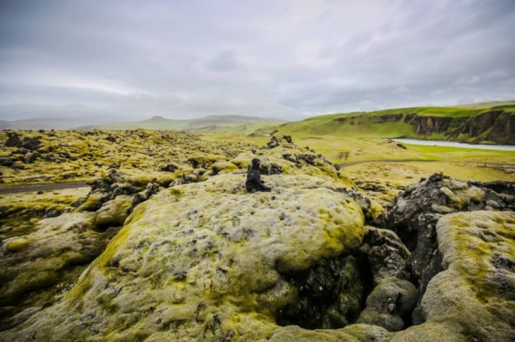 Persona sentada sobre los campos verdes en Islandia 