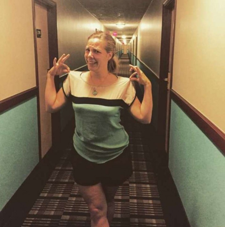 chica a la mitad del pasillo de un hotel vestida de colores iguales a los de las paredes 