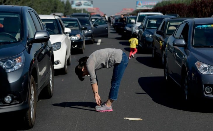 Mujer atorada en el tráfico haciendo ejercicio en medio de los coches 