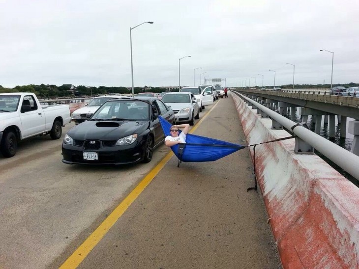 hombre acostado sobre una hamaca en medio de un embotellamiento 