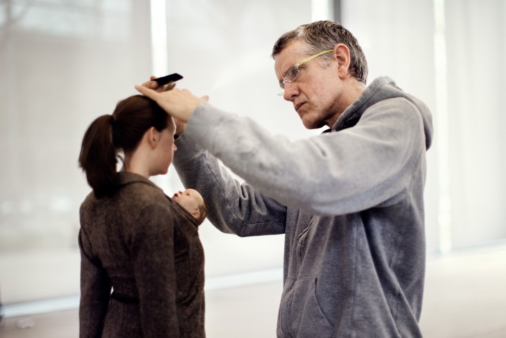 Ron Mueck dando detalles a una escultura en forma de mujer con un bebé en su pecho 