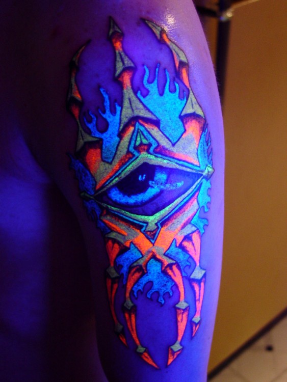 Tatuaje ultravioleta en forma de un ojo rodeado de lumbre en colores 