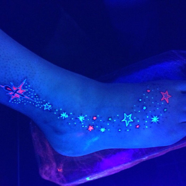 Tatuaje ultravioleta de un camino de estrellas en un pie 