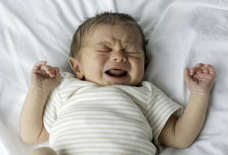 bebé recién nacido llorando sobre una cama 