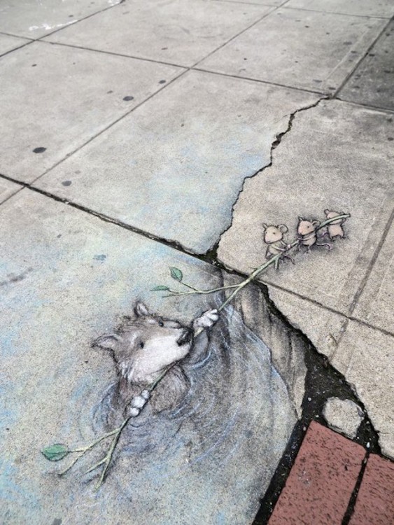 obra de arte en el suelo de una calle donde un osito está siendo salvado por tres ratones 