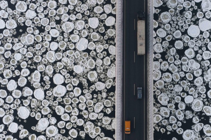 fotografía muestra carros que recorren un puente sobre un mar congelado 