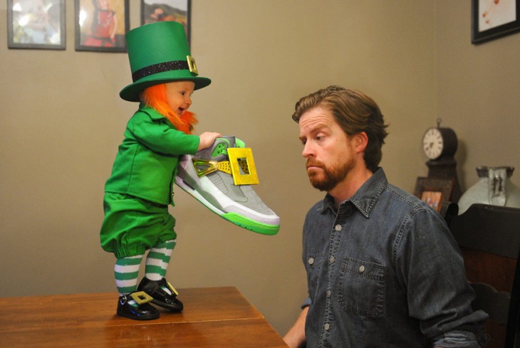 bebé disfrazado de leprechaun mostrando un teni a su papá 