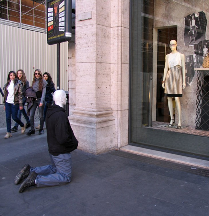 escultura de una persona real hincada frente un aparador 