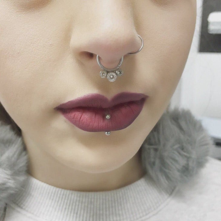 cara de una chica con piercings en la nariz y en un labio 