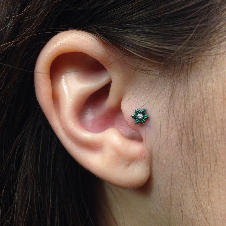 piercing en forma de flor en color verde cerca del oído