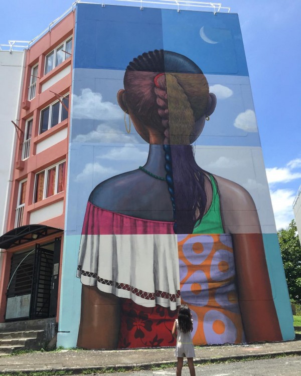 mural de un edificio con el dibujo de la parte trasera de una niña en Le Port