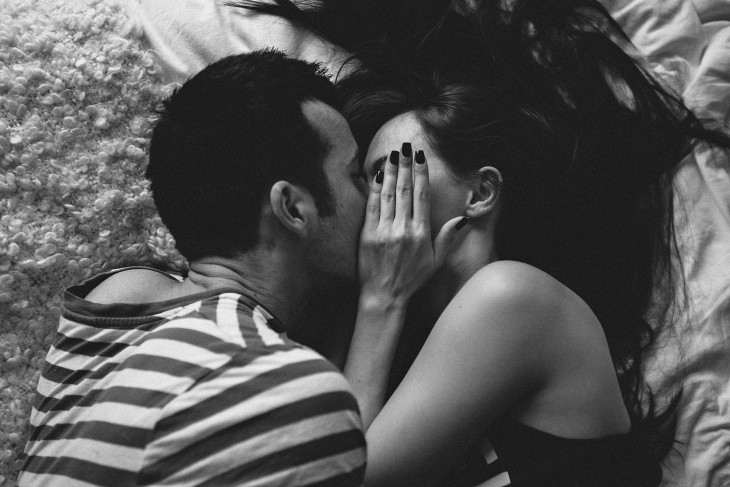 fotografía de una pareja tapándose la cara mientras se besan 