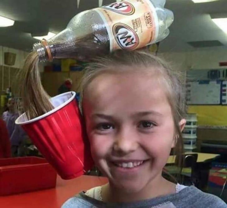 peinado de una niña simulando ser un refresco vaciándose sobre un vaso rojo 