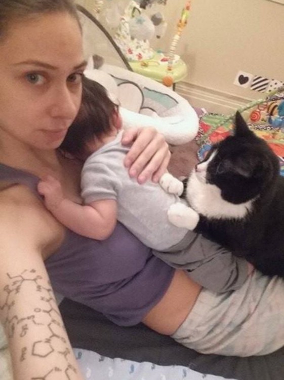 selfie de una chica que carga a su bebé y su gato 