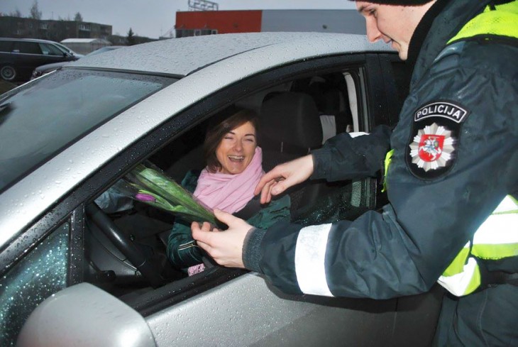 Mujer sonriendo mientras recibe flores de un policía en Lituania 