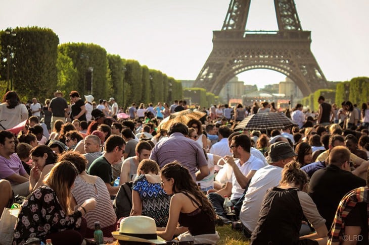 miles de personas sentadas frente a la torre eiffel