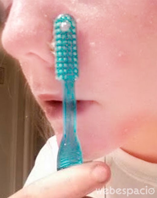 chica exfoliando su cara con un cepillo de dientes 