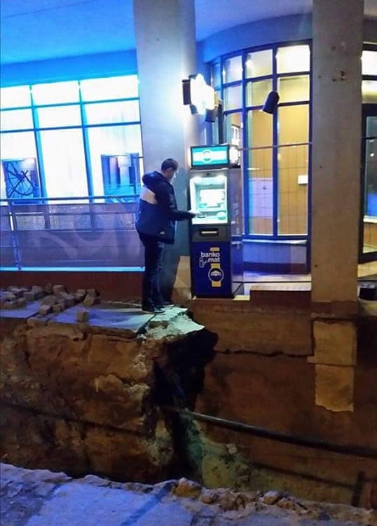 Hombre al borde de banqueta en reconstrucción usando un ATM