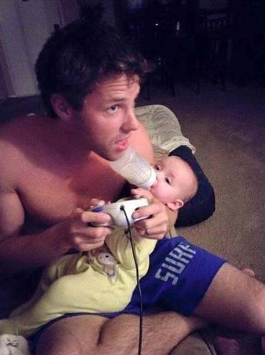 papá le da biberón a su hijo mientras juega videojuegos
