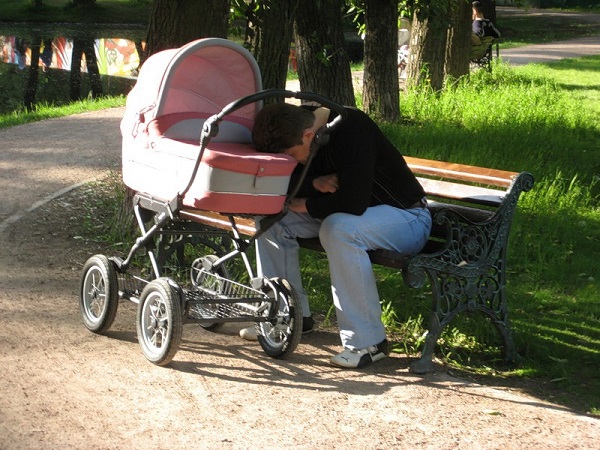papá se duerme en el parque mientras su bebé está en la carreola
