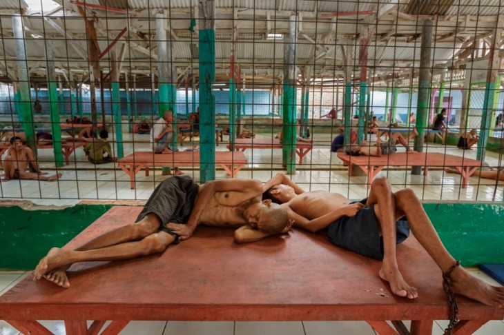 dos personas acostadas en una jaula de un hospital en Indonesia 