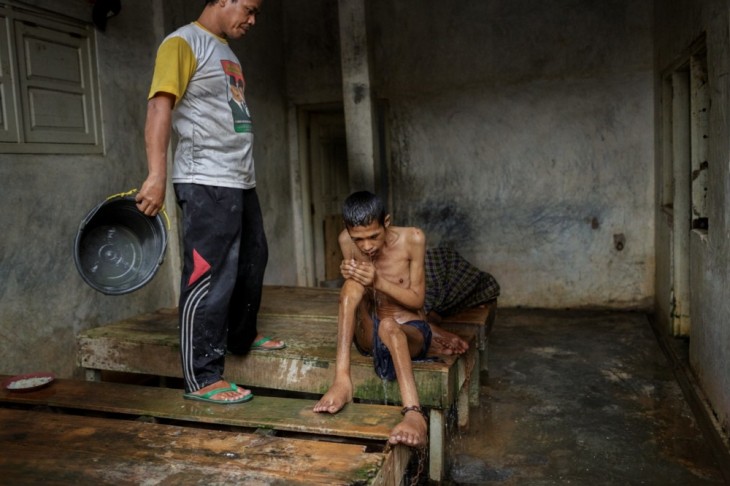 persona bañando a un paciente en un hospital mental de Indonesia 