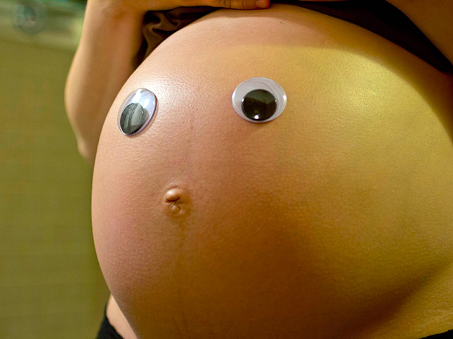 panza de una mujer embarazada con ojos de plástico 
