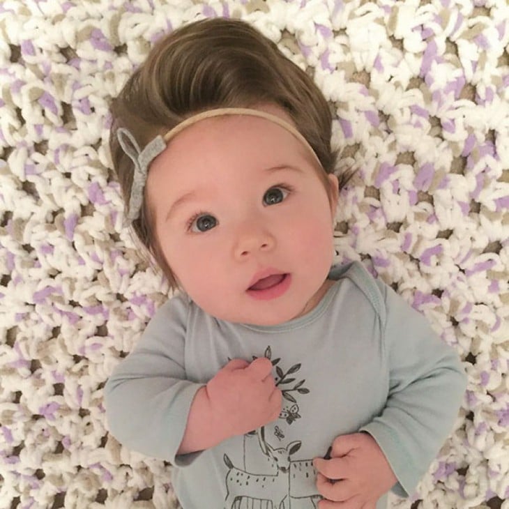 fotografía de una bebé acostada con una diadema en su cabello 