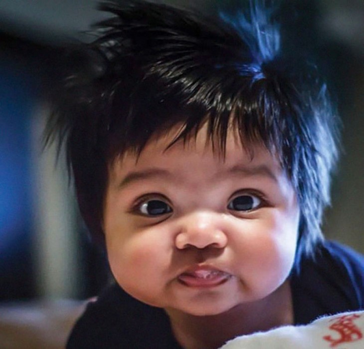 imagen de un bebé con mucho cabello y saliva en su boca 