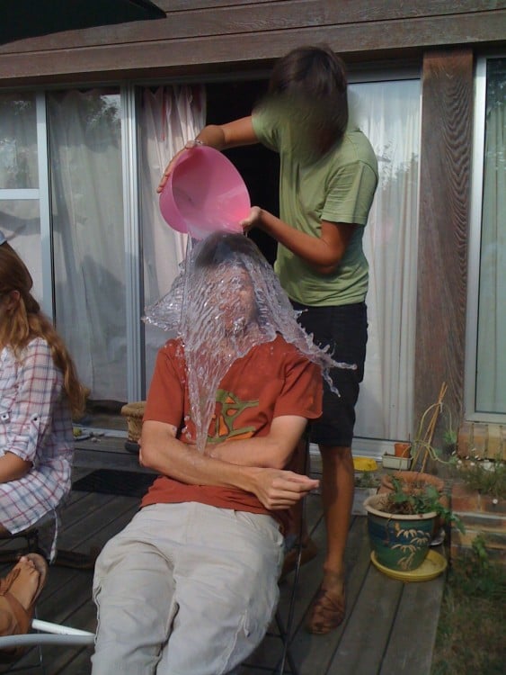 foto justo antes de que una mujer vacie una cubeta de agua sobre un chico 