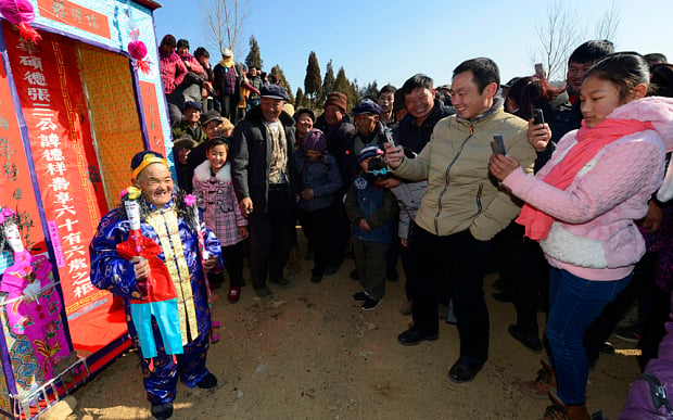 Hombre chino que fingió su muerte posando ante los celulares de varios aldeanos asistentes 