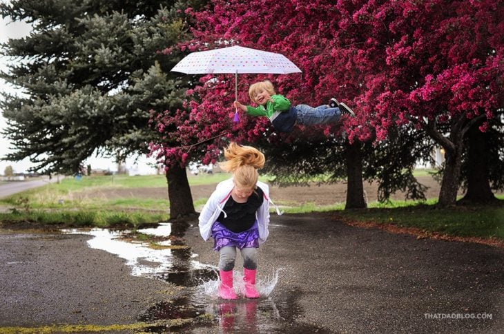 William, el niño con Síndrome de Down que puede volar, sosteniendo un paraguas arriba de su hermana mientras ésta brinca en un charco