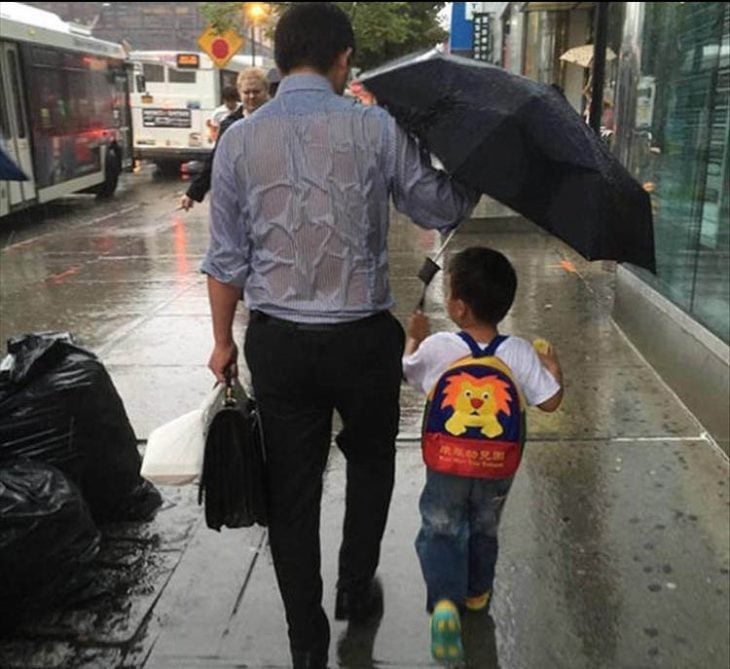 papá e hijo caminando en la lluvia y el papá va empapado pero el niño lleva el paraguas