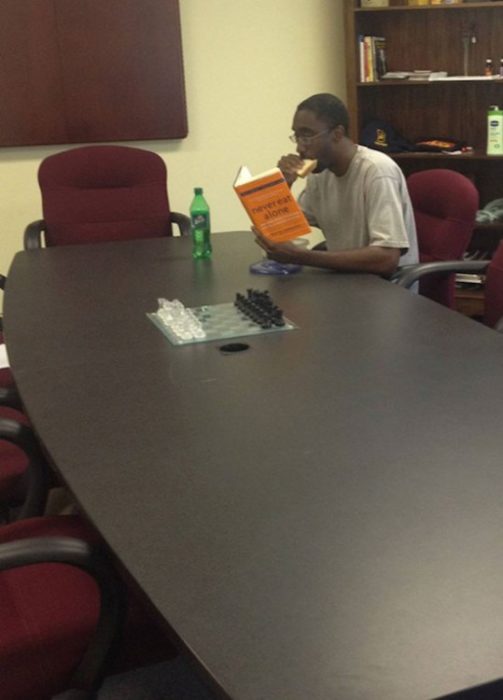 Ironía, hombre leyendo un libro de cómo nunca comer solo mientras come solo