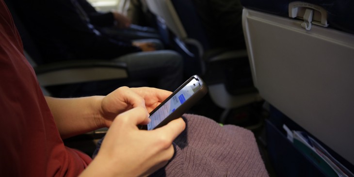 Pasajero de avión está enviando mensajes en su celular durante el vuelo