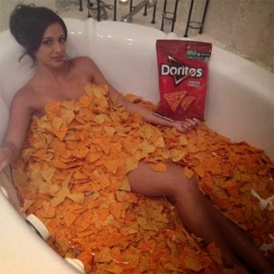 Situaciones embarazosas. Mujer desnuda en una tina llena de doritos