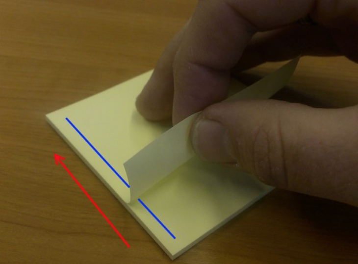 alguien separando post it de bloque con el pegamento del lado izquierdo