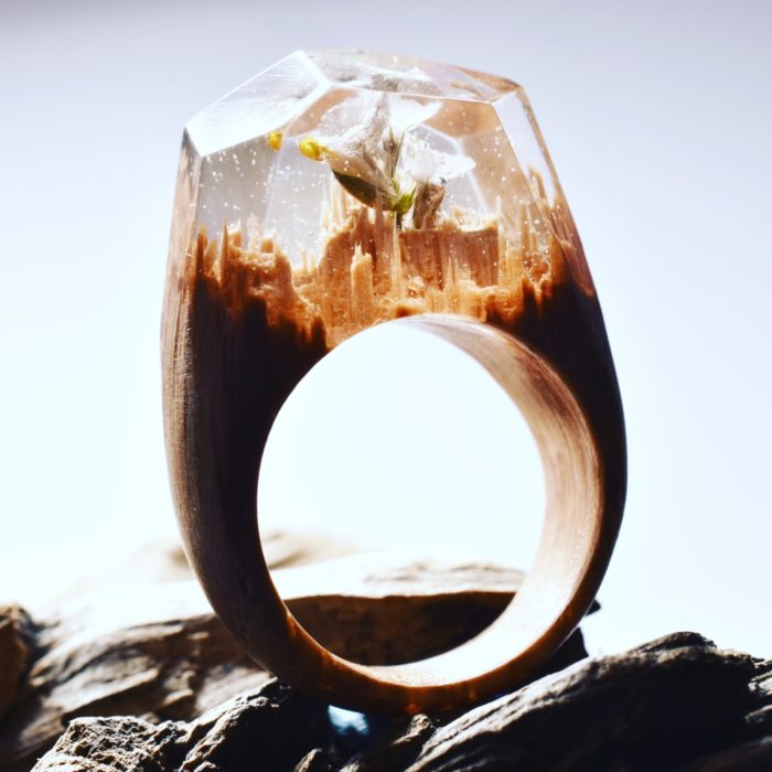 anillo de madera con un minipaisaje y una flor encapsulado en su interior 