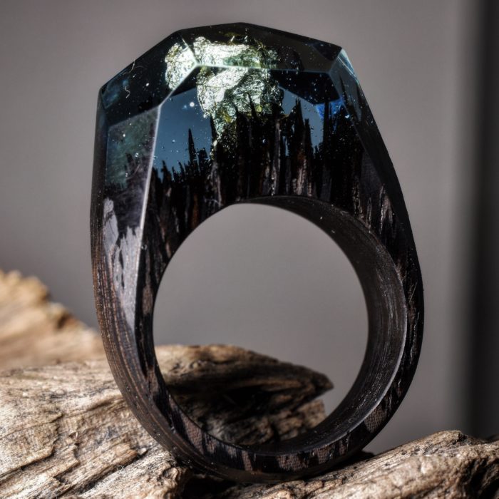 anillo de madera con un paisaje oscuro lleno de montañas y árboles 