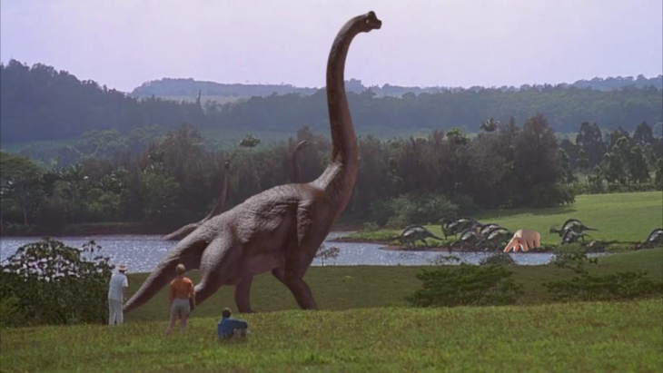 escena de un enorme dinosaurio con la mano de un bebé señalando 