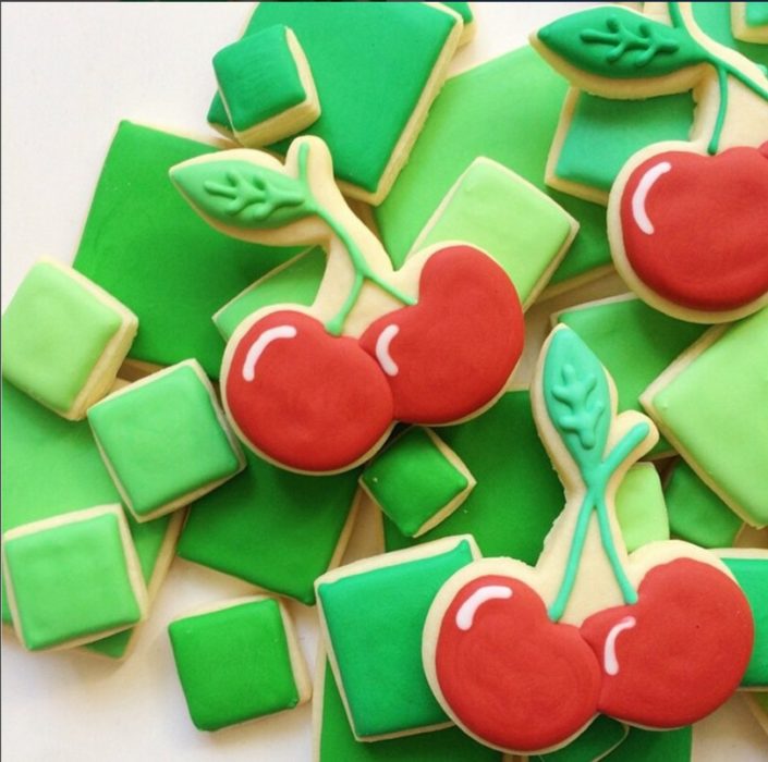 galletas en forma de cuadros verdes con algunas galletas en forma de cerezas 