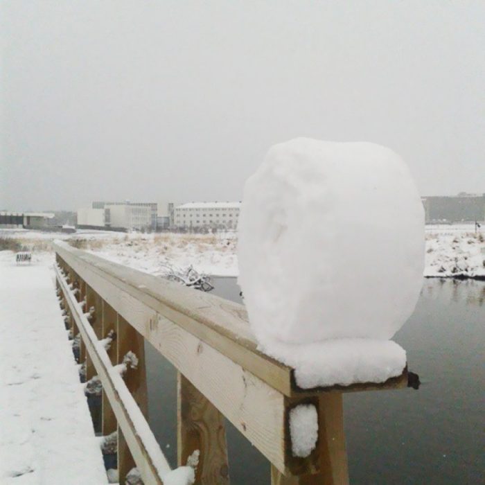 rollo de nieve sobre el barandal de un muelle