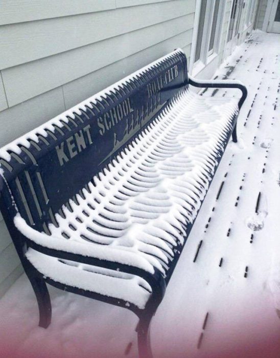 nieve sobre una banca en una calle 